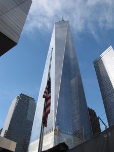 One World Trade Center (aka Freedom Tower), with a U.S. flag in the foreground, seen from the area where museumgoers wait for free tickets to the 9/11 Museum.