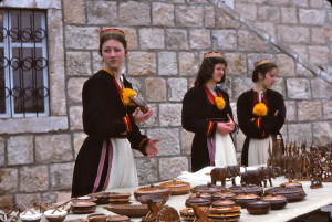 Young Cilipi women in traditional clothes for their region of the then Yugoslavia offer pottery and other goods for sale.