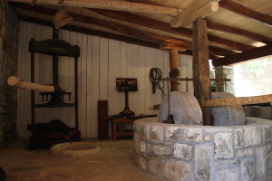 Millstones, at right, and a manually operated olive press, at left, set up as a display for visiting tourists at the Novakovic family farmhouse in Cilipi. The equipment is the same as that demonstrated early in the sightseeing itinerary for Viking Sea passengers. For the first, cold press of olives, the millstones would be pulled by a horse. The press at left would have been used with hot water to tease still more oil out of the olives.