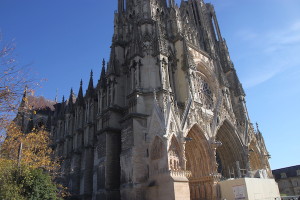 A Reims Cathedral photo showing which parts of the facade have been cleaned and which have not. The barricade blocking off a working area at the cathedral’s main door is visible at lower right.
