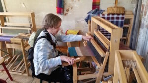 The author trying her hand at weaving after a demonstration at the Strawbery Banke Museum.