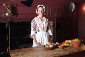 “Mrs. Margaret Davis,” who was set up to prepare a meal for 1777 guests at the Pitt Tavern, smiles upon seeing an invention from the future called the camera. 