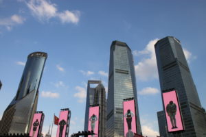 View of Shanghai high-rises seen from the grounds of the Oriental Pearl Tower. The pink screens, with images visible in the foreground, are actually on the tower grounds.