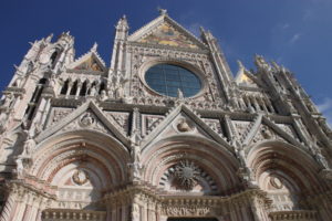 A similar view of the Siena Cathedral, seen at midday. While white marble predominates on the facade, the red marble is seen as part of the arches.