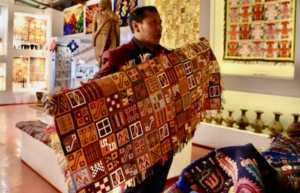 Above, on-site host at the Manos de la Comunidad displaying a handmade rug that features a traditional Inca design. Below, sample tapestry, a modern take on old themes, inside the commune showrooms.