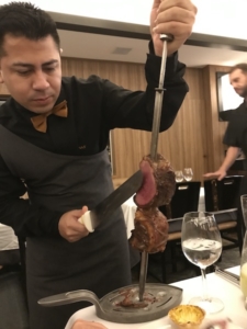 A waiter serves barbecued meat at the table for guests at the Churrascaria Palace.