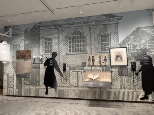 At “The Occupied City” exhibit, part of the display devoted to the 1783 emancipation of slaves who had served the British during the American Revolution and won passports to live free in other parts of the empire. The two figures who appear as silhouettes represent real people, one who escaped slavery and one who did not. Museum goers can pick up the single-cup headphones to hear each of the stories.