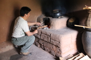 Stoking the fire before adding ground corn and flour to boiling water in the early phase of converting corn into the alcoholic drink, chicha de jora.