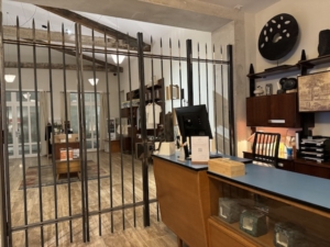 Reception desk at La Prison Hotel. In the background, the hotel shop, closed up during off hours by bars in keeping with the property’s origin story.