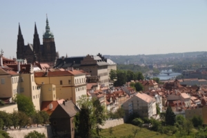 Parts of the Prague Castle complex, including St. Vitus Cathedral, at left, overlooking at center the rooftops of Prague’s Lesser Town. Bits of the Vltava River are visible in the background. Visitors can walk from the complex via Lesser Town to the Charles Bridge and beyond.